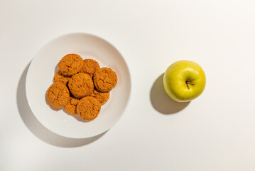 Cookies,Biscuits and green apple on white plate top view on white background.