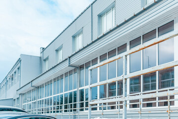 gray exterior aluminum panels facade with windows on industrial factory building.