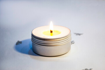 Close-up of a burning candle spreading fragrance on a table. Beautiful composition with massage...