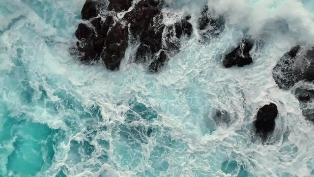 Aerial top down view of ocean surf crashes on the rocks. Stormy powerful waves in open Atlantic ocean