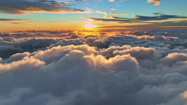 Camera rises above clouds, golden sunrise. Flying above the clouds illuminated by the morning sun. Epic sunrise in the sky. Aerial shot