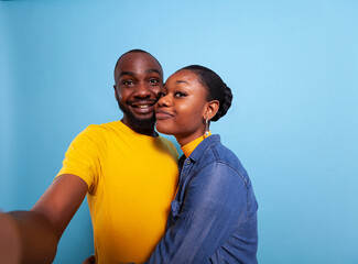 Obraz premium POV of people in relationship smiling in front of camera, taking pictures together in studio. Cheerful couple using phone in hand to take selfies and share romance. Partners hugging each other