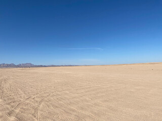 Desert landscape. Mountains on the horizon. Cloudless day. Walk in the desert. Buggy tracks.