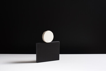 Queso cremoso de cabra sobre piedra negra y fondo negro. Concepto minimalista	