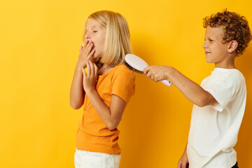 a boy with a comb combing a girl's hair yellow background