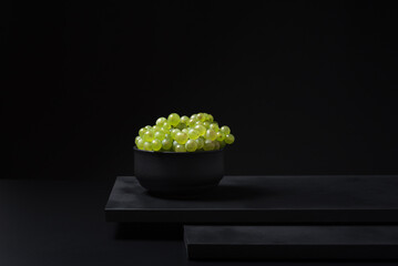 Uvas de vino blanco en un recipiente sobre fondo negro
