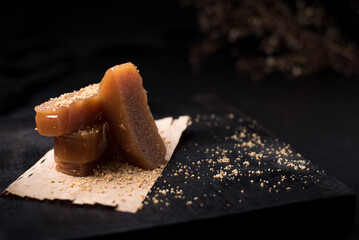 Dulce pasta de gelatina de membrillo dorado sobre una placa de madera negra