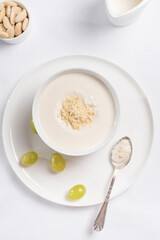 Crema de almendras, sopa fría española. Ajo blanco de Málaga con almendras y uvas en un recipiente blanco sobre una mesa blanca. Vista superior