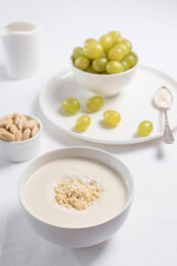 Crema de almendras, sopa fría española. Ajo blanco de Málaga con almendras y uvas en un recipiente blanco sobre una mesa blanca	