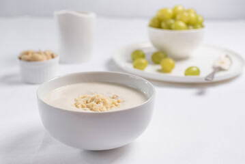 Crema de almendras, sopa fría española. Ajo blanco de Málaga con almendras y uvas en un recipiente blanco sobre una mesa blanca	