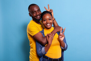 Couple hugging and showing peace sign with fingers on camera, feeling happy in relationship....