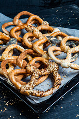 Fresh prepared homemade soft pretzels. Different types of baked bagels with seeds on a black background.