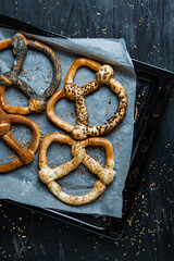 Fresh prepared homemade soft pretzels. Different types of baked bagels with seeds on a black background.