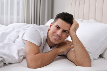 Happy man lying in bed at home
