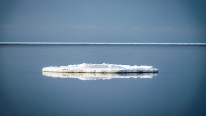 white pieces of ice floating in the sea, winter landscape from the sea, calm water, sky reflections in the sea