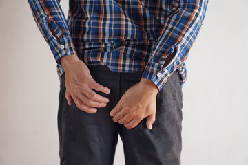 Closeup man's hands hold his bottom. Concept : getting hemorrhoids, diarrhea, pain in bottom from...