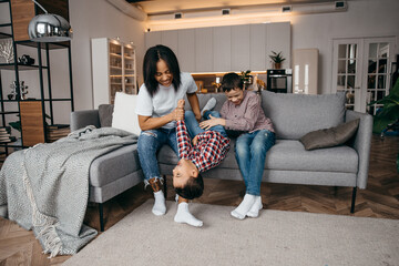 Obraz premium Happy african american family mom and two sons fooling around and having fun at home together