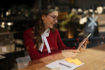 Beautiful young woman using digital tablet in cafe. Happy smiling woman enjoy in fresh coffee..