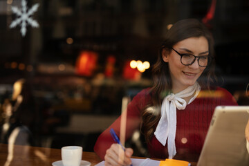 Beautiful young woman using digital tablet in cafe. Happy smiling woman enjoy in fresh coffee..