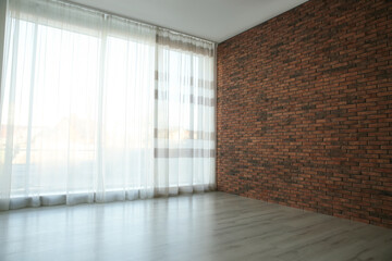 Fototapeta premium Empty room with red brick wall, large window and wooden floor