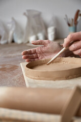 Female ceramist working in pottery studio. Ceramist's Hands Dirty Of Clay. Process of creating pottery. Master ceramist works in her studio