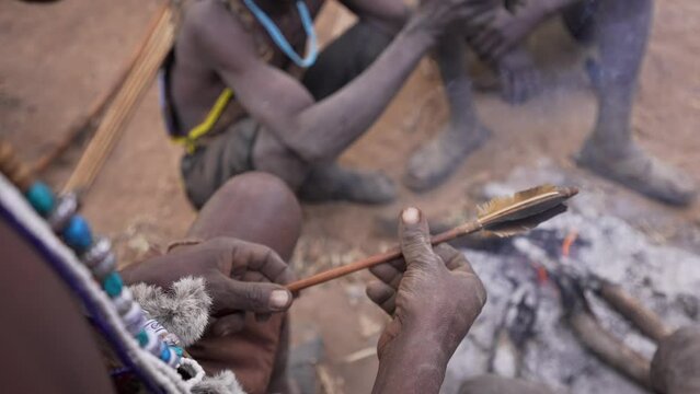 Close up cinematic shot of a hunter African tribe man preparing an arrow before hunt. Bushmen. Tanzania, Africa 4K