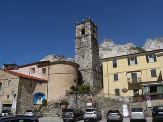 Fototapeta na wymiar Square with the stone bell tower of Colonnata with in the backgound the marble quarries of the Apuan Alps
