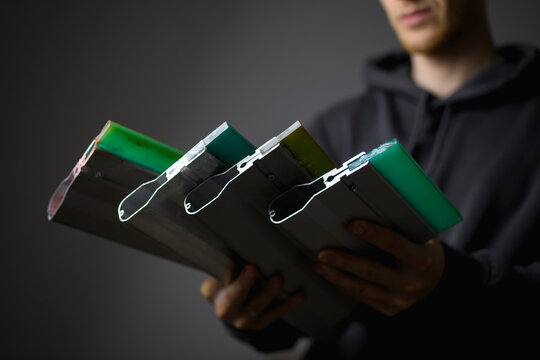 Squeegees for screen printing in hands of blurred craftsman isolated on grey 