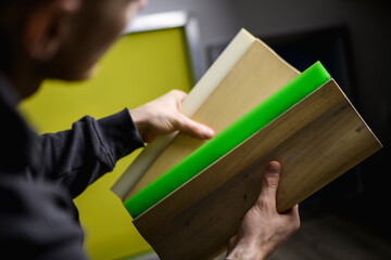 Partial view of designer holding serigraphy squeegees in workshop 