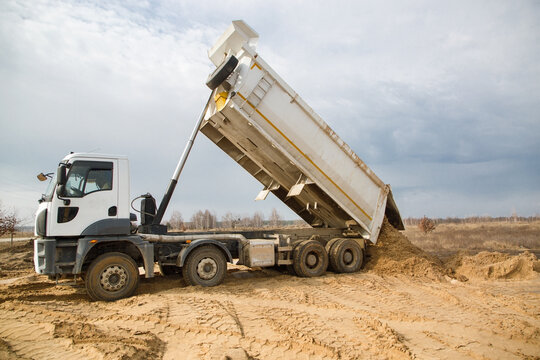 dump truck with a raised body at a construction site in the process of unloading soil. Site preparation for construction, earthworks