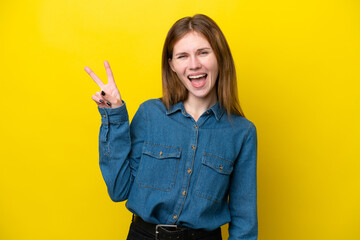 Young English woman isolated on yellow background smiling and showing victory sign