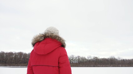 Woman in warm hooded winter coat standing outdoors in white snowy frosty countryside landscape background. Christmas season © Andrii Oleksiienko