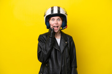 Young English woman with a motorcycle helmet isolated on yellow background with surprise and shocked facial expression