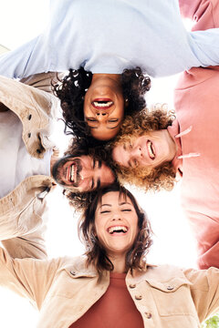 Vertical photo of a Circle of four happy young people looking at the camera embracing and having a fun.
