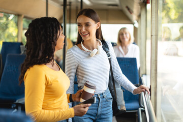 Cheerful multiethnic smiling women standing in bus and talking © Prostock-studio
