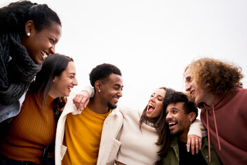 Multi-ethnic group of friends hugging and having fun. Isolated young smiling people laughing...