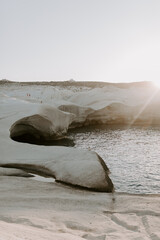 The sandstone white rocks cliffs moonscape of Sarakiniki volcanic beach in Milos Island Greece surrounded by turquoise blue waves and sea at sunset