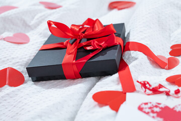 Gift box packed and postcard decorated with a red beautiful bow on the bed. Valentine's day, Birthday love gift