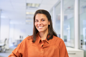 Lächelnde Geschäftsfrau im Großraumbüro als Chefin
