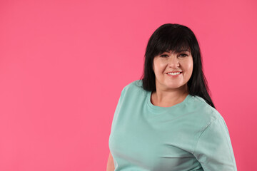 Fototapeta premium Beautiful overweight mature woman with charming smile on pink background. Space for text
