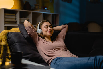 woman relaxing at home listening music on headphones