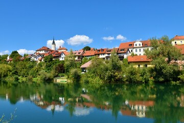 Naklejka na ściany i meble View of the old town of Novo Mesto in Dolenjska, Slovenia with a reflection of the buildings and trees in Krka river