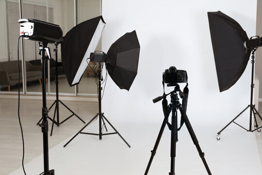 Tripod with camera and professional lighting equipment in photo studio