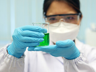 The scientist wear PPE and hold a beaker laboratory, with green solvent solution from reaction boric acid with mixed indicator titration experiment, Nitrogen analysis compounding in wastewater sample.