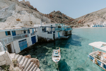 Relaxing scene by the secret cove in Milos Island Greece surrounded by idyllic landscape, turquoise water,  fisherman houses, mountains and blue skies. 
