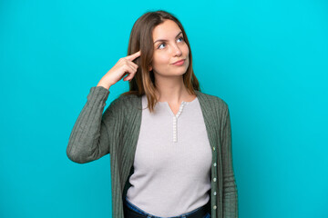 Young caucasian woman isolated on blue background making the gesture of madness putting finger on...