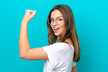 Young caucasian woman isolated on blue background With glasses and celebrating a victory