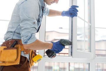 Man fixing lock to window with electric screwdriver