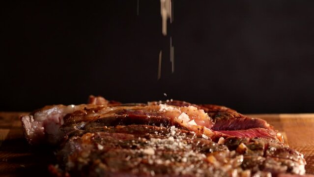 Salting  juicy beef rib eye steak on a wooden board