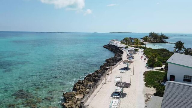 Aerial drone footage of the beautiful Pearl Island in the Bahamas near Nassau, showing the beach and lighthouse of the tropical island and beautiful green clear ocean